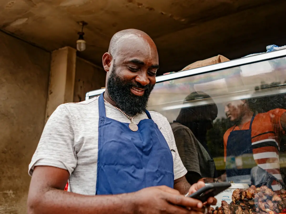 A market trader in an apron checks his smartphone