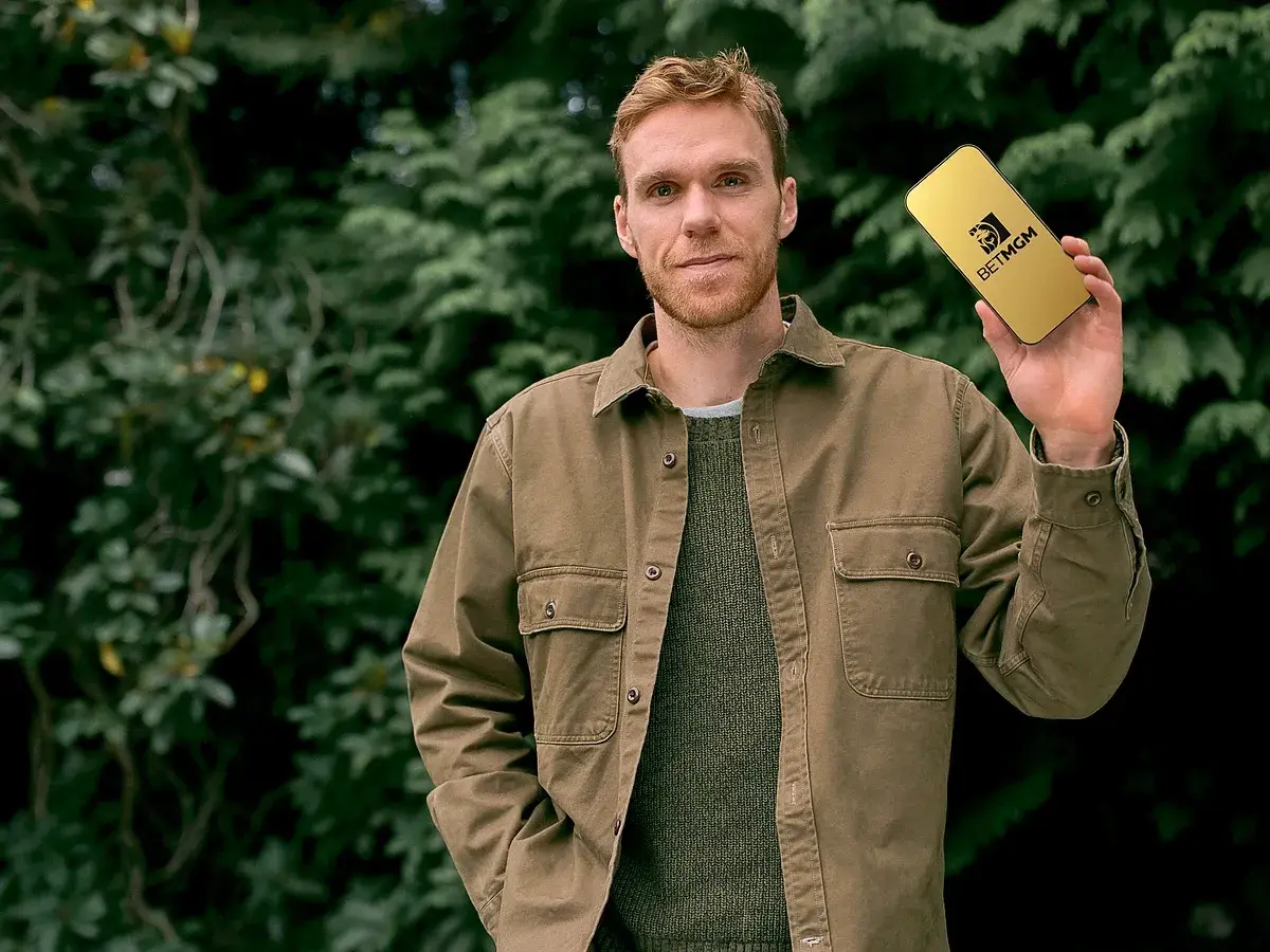 Connor McDavid holding a phone displaying the BetMGM logo