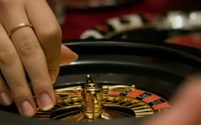 Dealer spinning a roulette wheel at a live casino table
