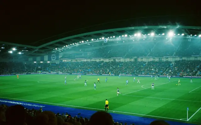 Floodlit football stadium during a night match
