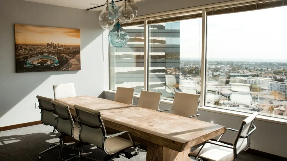 Empty boardroom with a long wooden conference table and a city view