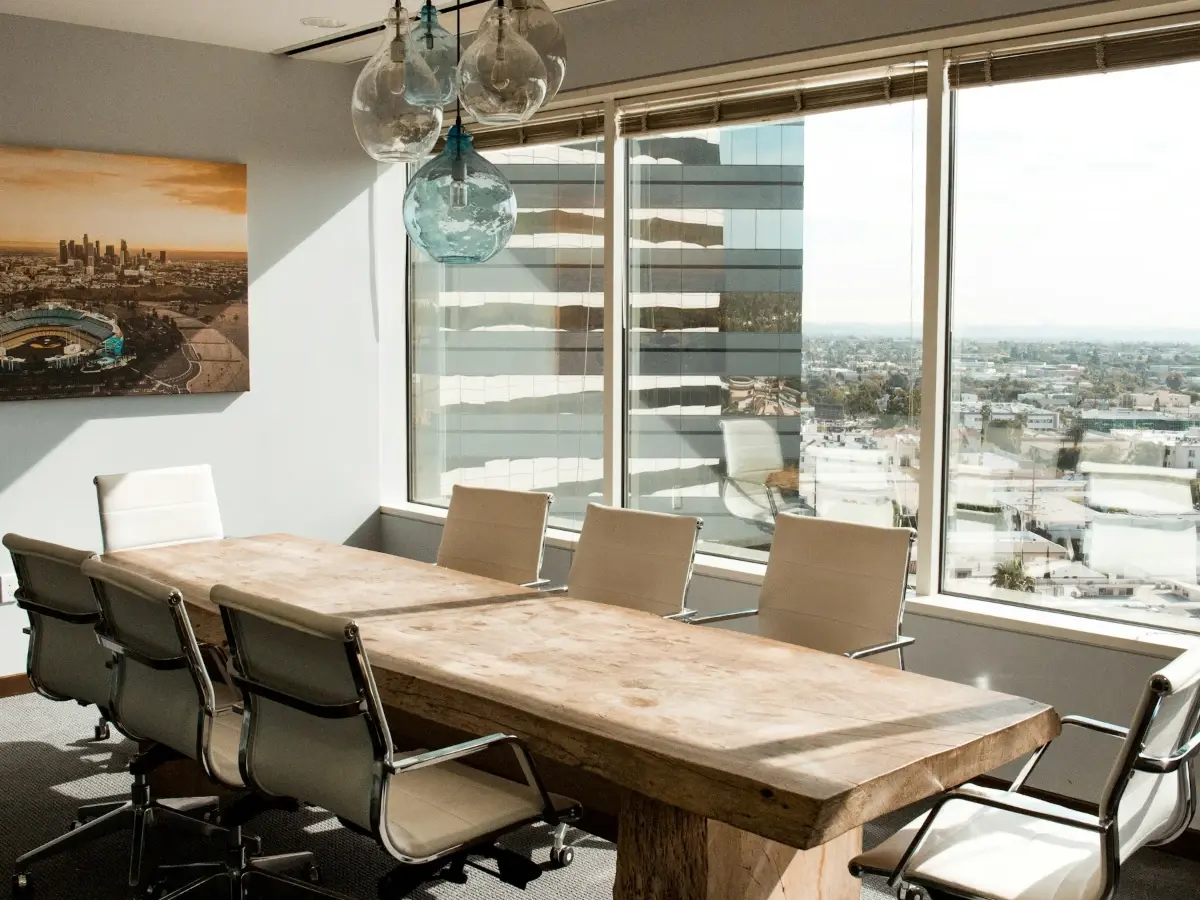 Empty boardroom with a long wooden conference table and a city view
