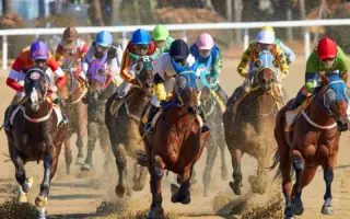Jockeys and horses racing on a dirt track