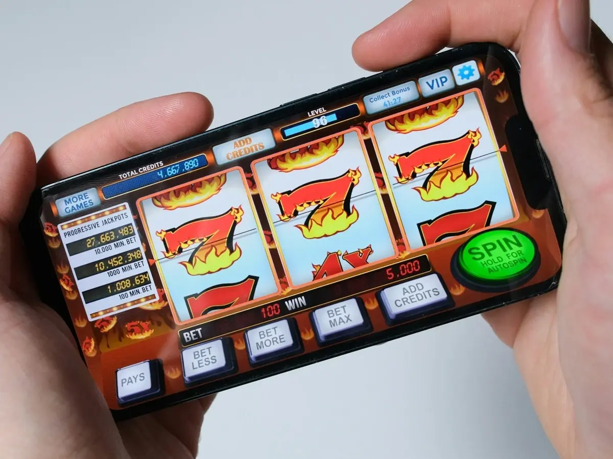 Hands holding a smartphone showing a slot game